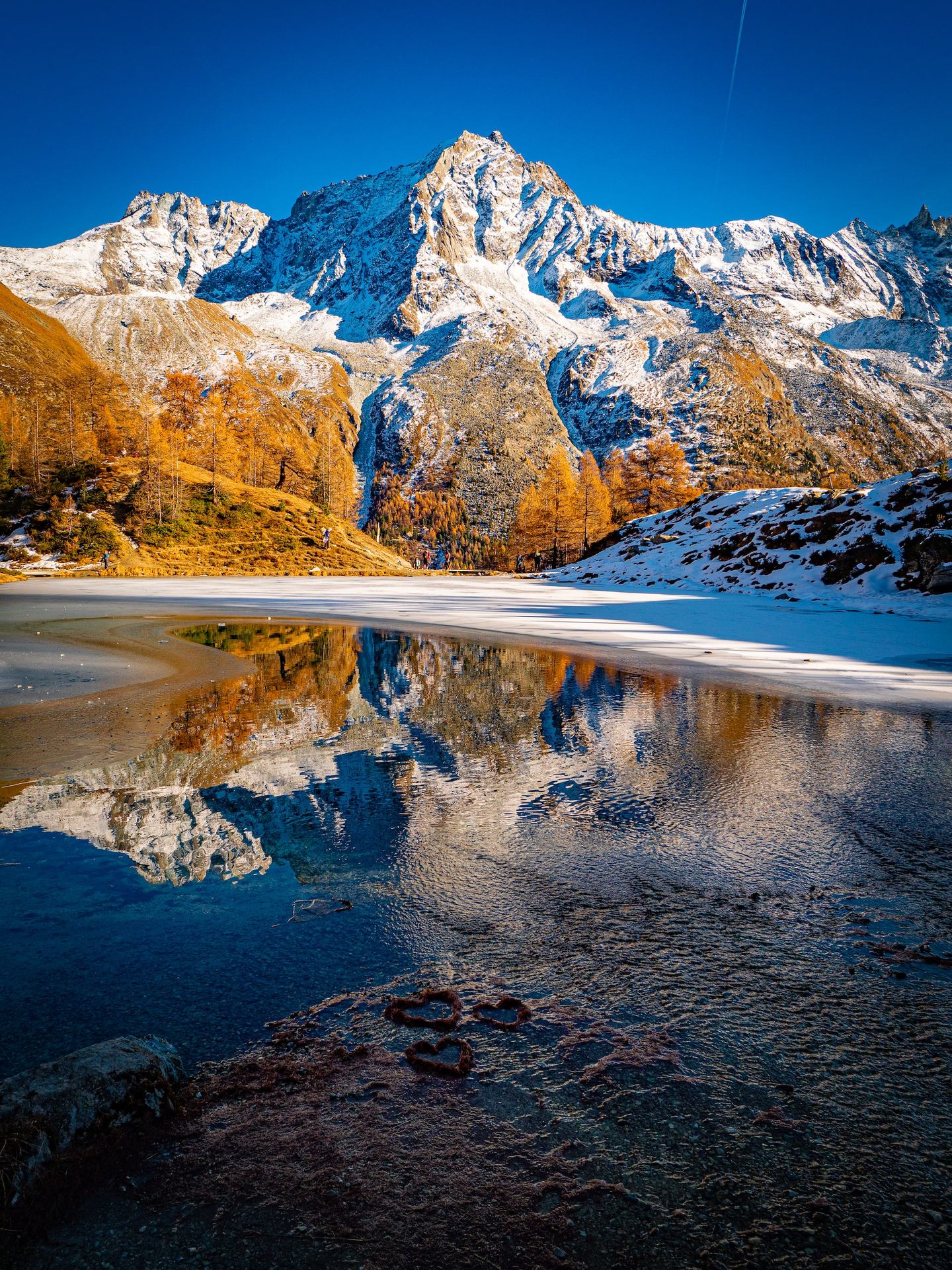 a snow covered mountain with a lake in the foreground